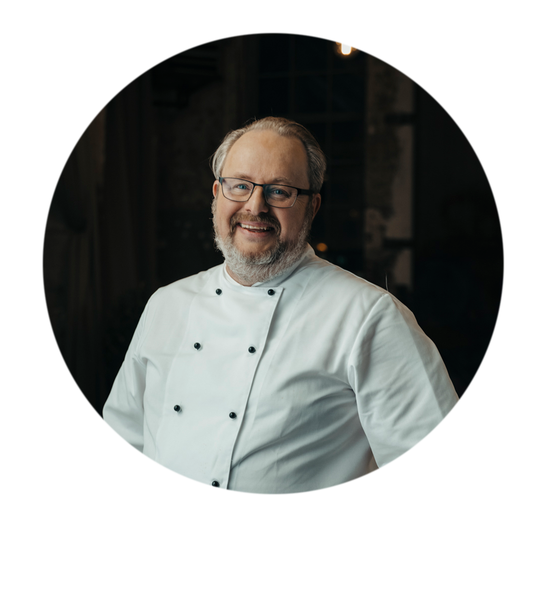 Bildporträtt av Joakim Lundblad med glasögon iklädd i klassisk kockoutfit 