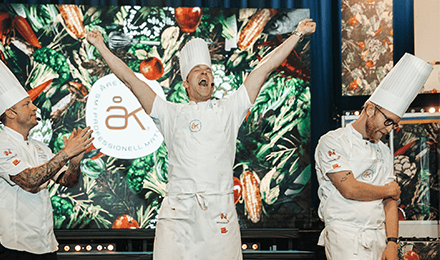 En glad vinnare av Årets Kock höjer sina armar i luften av lycka